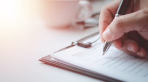 Image of close up hand writing on a survey with a pen